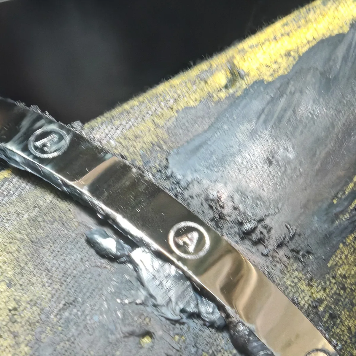 Gold bangle with engraved letter A roundels at the bench before final polishing