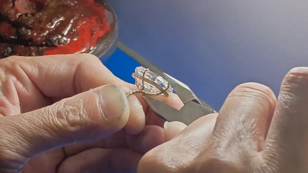 Setter pressing the prongs onto a 20.06 carat emerald cut lab grown diamond with pliers at the bench